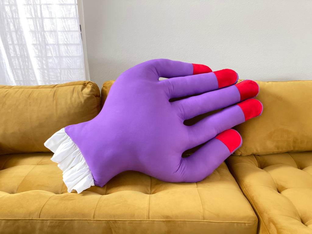 Purple Hand Throw Pillow on a Mustard Yellow Couch 